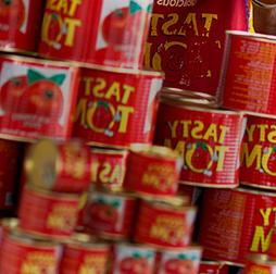 A stack of Tasty Tom tins full of tomato paste, 推荐买球平台还生产意大利面, 饼干, yoghurt drinks and edible oils for African markets.